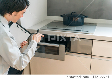 一位來自設備公司/建築公司的穿著工作服的男性商人檢查廚房 IH 爐子上的烤架 112172761