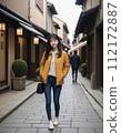 年輕女子穿過一條兩旁都是日本老房子的街道 112172887
