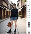 年輕女子穿過一條兩旁都是日本老房子的街道 112172892