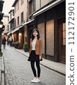 年輕女子穿過一條兩旁都是日本老房子的街道 112172901