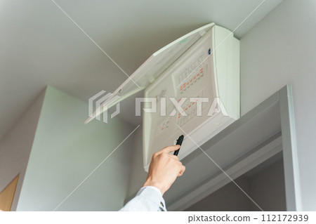 At hand of a worker checking the distribution board, switchboard, and breaker At hand of a worker checking the distribution board, switchboard, and breaker 112172939