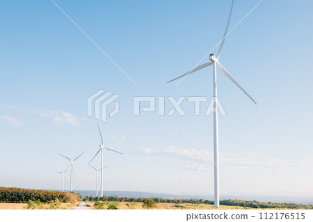 In a scenic prairie windmill farm turbines generate clean power on a mountain. A symbol of sustainable development and innovative wind technology against a blue sky. 112176515