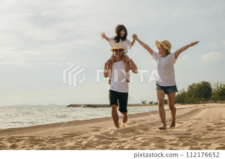 Road trips day. Happy family people having fun in summer vacation on beach, daughter riding on father back and mother running race at sand beach, enjoying road family trip playing together outdoor 112176652