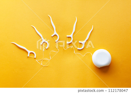 concept of dental hygiene, plastic dental floss on yellow background 112178047
