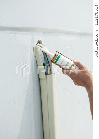 sealing  air conditioner hose with caulk for installation  air conditioner outdoor unit 112179914