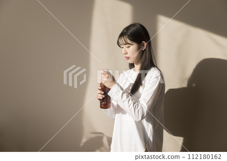 Young woman opening a plastic bottle of tea indoors 112180162