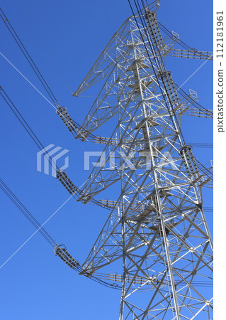 High-voltage power transmission line tower towering against the blue sky 112181961