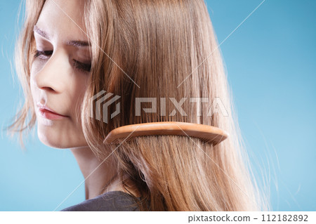Female combing hair with wooden comb Female combing hair with wooden comb 112182892