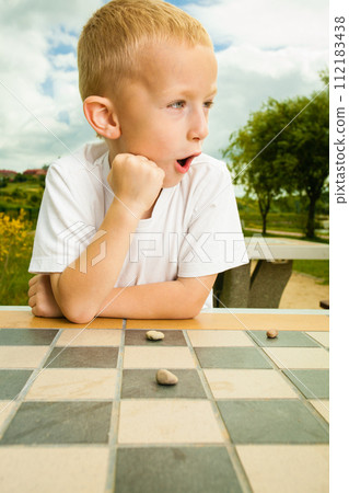 Child playing draughts or checkers board game outdoor 112183438