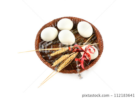 Easter eggs in a wicker basket isolated on a white . 112183641