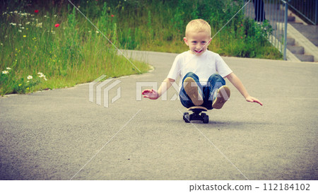 Child kid sitting on skateboard having fun outdoor 112184102