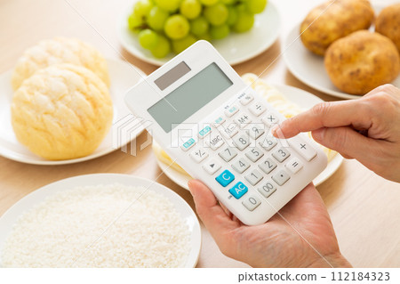 中年婦女吃含有大量糖（碳水化合物）的食物和計算器 112184323