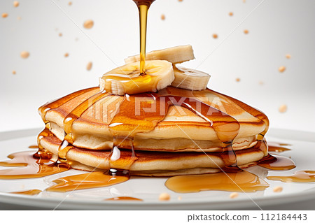 Stack of pancakes with maple syrup and banana slices on top. 112184443