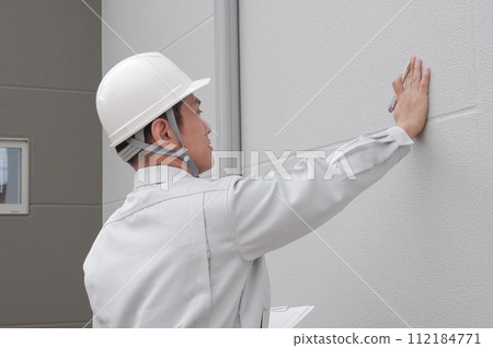 A worker checking the exterior wall 112184771