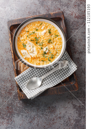 Italian pastina soup with chicken, vegetables and cheese close-up in a bowl. Vertical top view 112185193