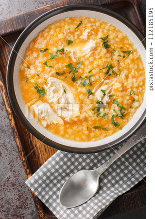 Italian chicken pastina soup with parmesan close-up on a bowl on a wooden board. Vertical top view 112185195