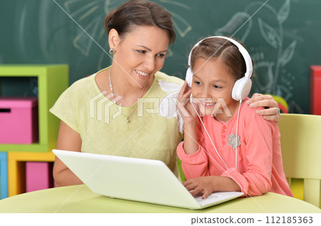Portrait of mother and daughter using laptop 112185363
