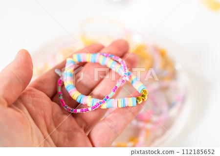 Little girl's charming bracelets adorned with clay and sea beads. 112185652