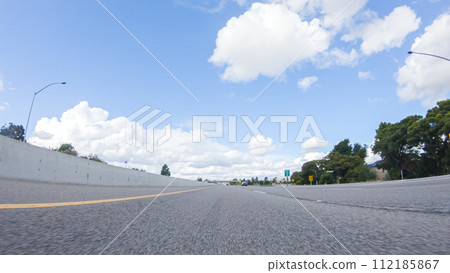 On a clear winter day, a car smoothly travels along Highway 101 near Santa Maria, California, under a brilliant blue sky, surrounded by a blend of greenery and golden hues. On a clear winter day, a car smoothly travels along Highway 101 near Santa Maria, California, under a brilliant blue sky, surrounded by a blend of greenery and golden hues. 112185867