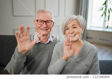 Happy senior woman man talk on video call with friends family. Mature old grandmother grandfather talking speaking with grown up children online. Older generation modern tech usage. Webcamera view Happy senior woman man talk on video call with friends family. Mature old grandmother grandfather talking speaking with grown up children online. Older generation modern tech usage. Webcamera view 112186009