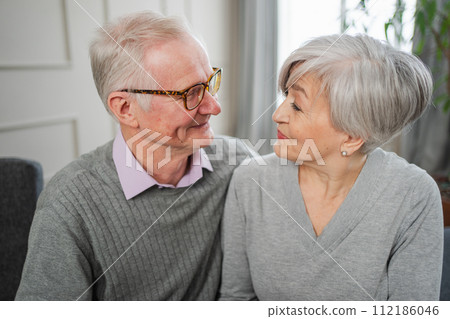 Senior adult mature couple hugging at home. Mid age old husband and wife embracing with tenderness love enjoying sweet bonding wellbeing. Grandmother grandfather together. Family moment love and care Senior adult mature couple hugging at home. Mid age old husband and wife embracing with tenderness love enjoying sweet bonding wellbeing. Grandmother grandfather together. Family moment love and care 112186046