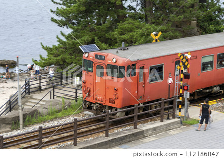 冰見線太良子號列車穿過雨晴海岸岩木義經旁的鐵路道口。 冰見線太良子號列車穿過雨晴海岸岩木義經旁的鐵路道口。 112186047