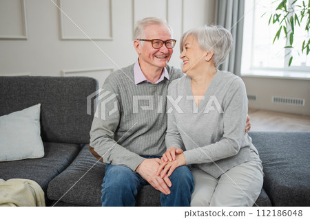Senior adult mature couple hugging at home. Mid age old husband and wife embracing with tenderness love enjoying sweet bonding wellbeing. Grandmother grandfather together. Family moment love and care Senior adult mature couple hugging at home. Mid age old husband and wife embracing with tenderness love enjoying sweet bonding wellbeing. Grandmother grandfather together. Family moment love and care 112186048