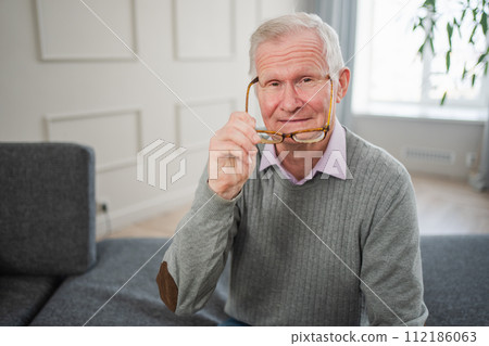 Portrait of confident stylish European middle aged senior man at home. Older mature 70s man smiling. Happy attractive senior grandfather looking camera close up face headshot portrait. Happy people Portrait of confident stylish European middle aged senior man at home. Older mature 70s man smiling. Happy attractive senior grandfather looking camera close up face headshot portrait. Happy people 112186063
