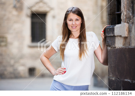 Young woman standing near old stone wall 112186134