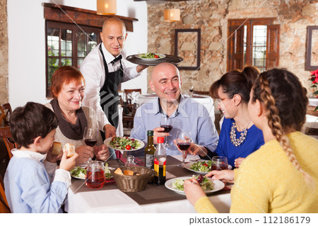 Waiter serving salad to family Waiter serving salad to family 112186179