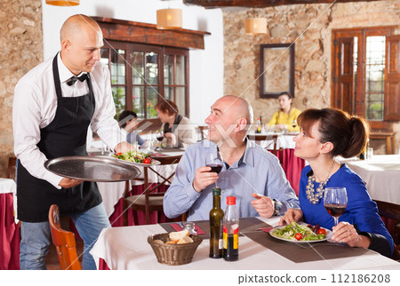 Cheerful waiter serving plates Cheerful waiter serving plates 112186208