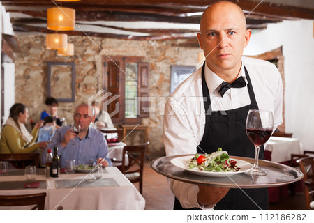 Positive waiter with tray at restaurant Positive waiter with tray at restaurant 112186282