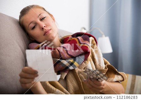 Sad young female reading recipe with pills 112186283