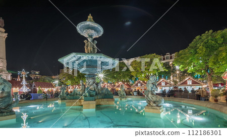 Panorama showing illuminated fountain with holiday decorations at the Rossio Christmas Market timelapse on Dom Pedro IV square. Lisbon, Portugal Panorama showing illuminated fountain with holiday decorations at the Rossio Christmas Market timelapse on Dom Pedro IV square. Lisbon, Portugal 112186301