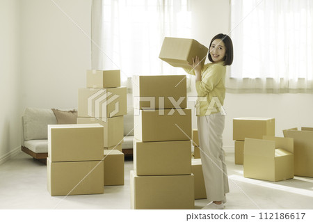 Young woman stacking cardboard boxes for moving 112186617
