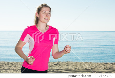 Sporty woman running on ocean beach 112186780