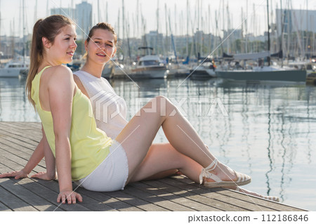 Portrait of young traveling girls sitting on promenade sea 112186846