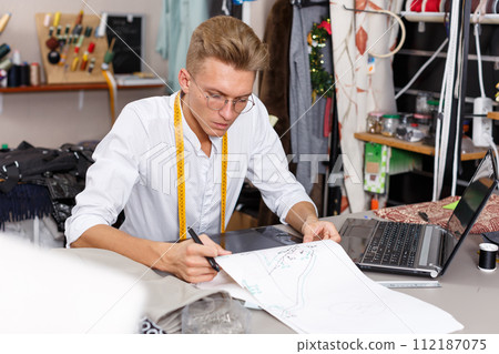 Tailor using laptop and graphics tablet 112187075