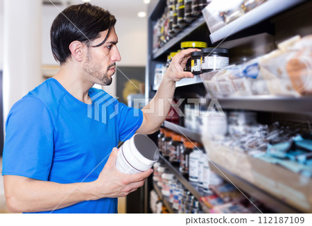 Serious muscular sportman choosing sport dietary supplements 112187109