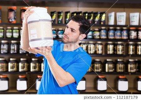 Serious sportman looking different sport nutrition products Serious sportman looking different sport nutrition products 112187179