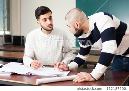 Guys working on student project at desk 112187200