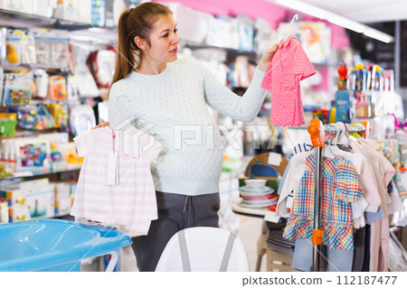 calm pregnant female is buying clothes for baby in thestore calm pregnant female is buying clothes for baby in thestore 112187477