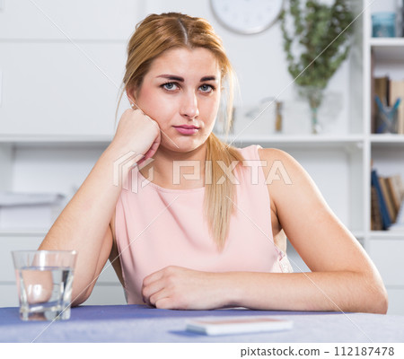Sad woman is sitting at the table alone and upset Sad woman is sitting at the table alone and upset 112187478