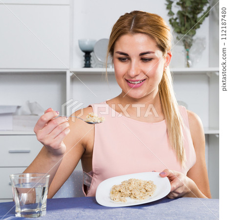 Sporty girl is enjoying breakfast with oatmeal porridge Sporty girl is enjoying breakfast with oatmeal porridge 112187480