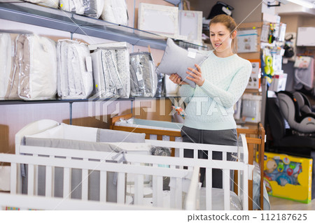 woman is choosing pillow for baby crib 112187625