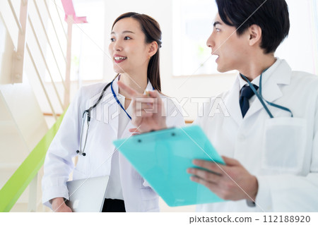 走在醫院裡的年輕男性和女性醫生 走在醫院裡的年輕男性和女性醫生 112188920