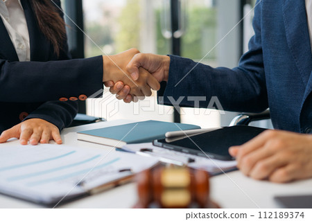 Lawyer shaking hands with client after discussing final contract agreement. Lawyer shaking hands with client after discussing final contract agreement. 112189374