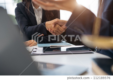 Lawyer shaking hands with client after discussing final contract agreement. Lawyer shaking hands with client after discussing final contract agreement. 112189376