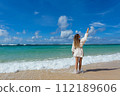 Young woman  stands barefoot on the beach 112189606