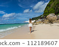 Young woman walks barefoot on the beach 112189607